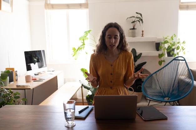 Foto blanke vrouw die tijd thuis doorbrengt, zichzelf isoleert en sociale afstand neemt in quarantaine-afsluiting tijdens de coronavirus covid 19-epidemie, met behulp van laptop, videobellen