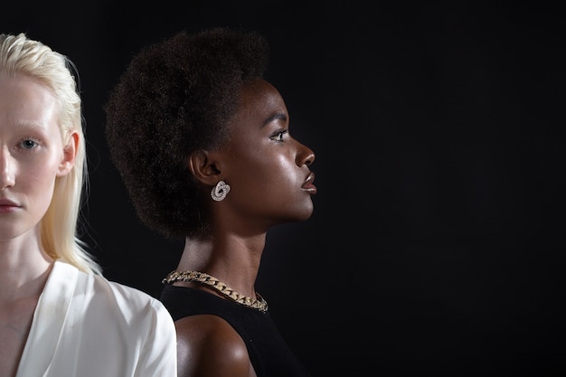 Blanke vrouw en Afro-Amerikaanse vrouw portret op zwarte achtergrond. Vrouwen vriendschap, liefde en relaties concept.