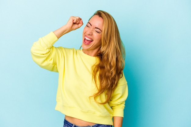 Blanke vrouw geïsoleerd op blauwe achtergrond die een overwinning, passie en enthousiasme, gelukkige uitdrukking viert.