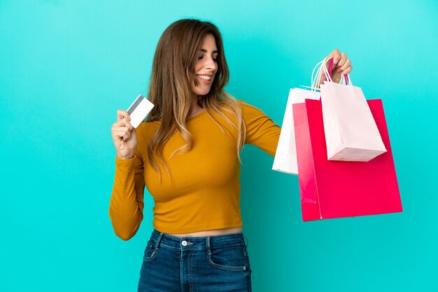 Blanke vrouw geïsoleerd op blauwe achtergrond met boodschappentassen en een creditcard