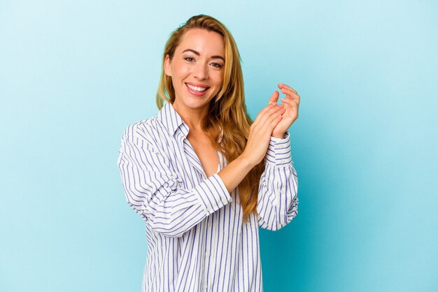 Blanke vrouw geïsoleerd op blauwe achtergrond voelt zich energiek en comfortabel, wrijft zelfverzekerd over de handen.