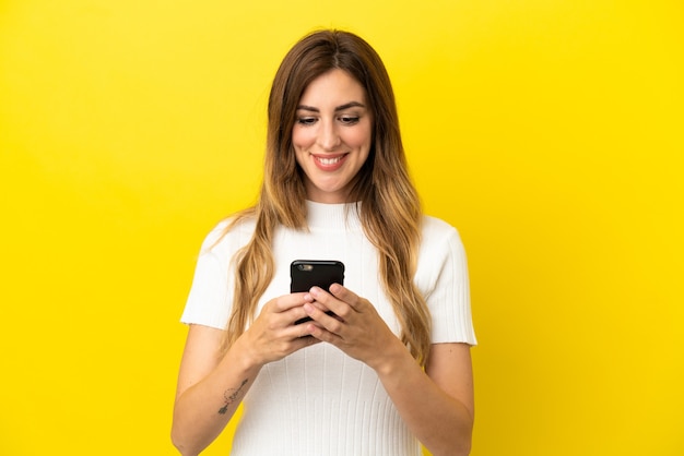 Blanke vrouw geïsoleerd op gele achtergrond die een bericht of e-mail verzendt met de mobiel