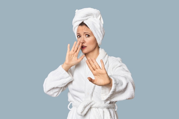 blanke vrouw in badjas en handdoek die wordt geschokt vanwege een dreigend gevaar