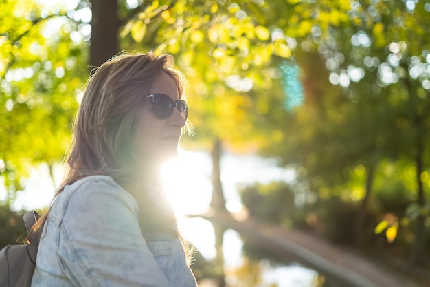 Blanke vrouw in een tegenlicht portret met de herfstzon die van achteren opwarmt in een zonsondergang