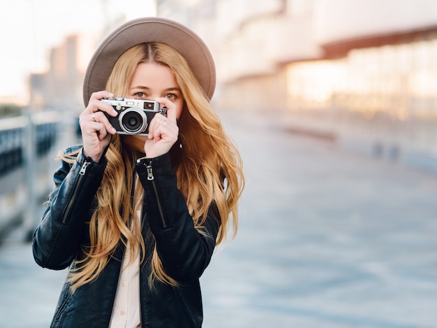 Blanke vrouw in hoed met camera buitenshuis