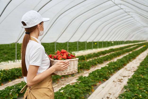 Blanke vrouw in masker met mand met aardbeien