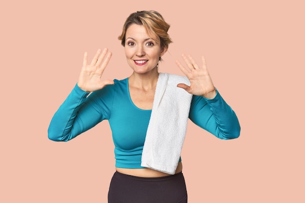 blanke vrouw in sportkleding met handdoek met nummer tien met handen