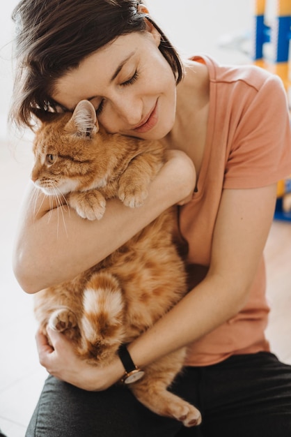 Blanke vrouw knuffelen met liefde haar rode maine coon kitten mooi meisje mooie vrouwelijke persoon een...