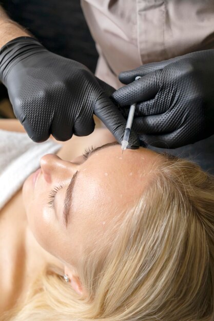 Foto blanke vrouw krijgt botox cosmetische injectie in het voorhoofd schoonheid arts zet naald van