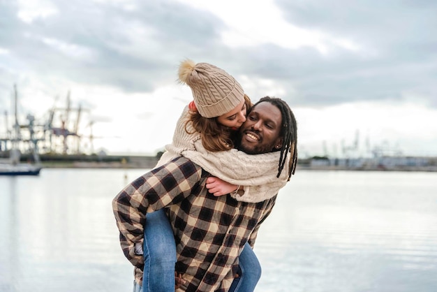 Blanke vrouw kust haar afro-amerikaanse vriend op de wang terwijl ze geniet van een ritje op de rug