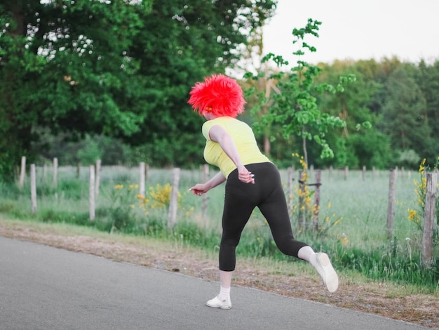 Blanke vrouw met een pruik met Belgische vlag loopt in een grappige marathon