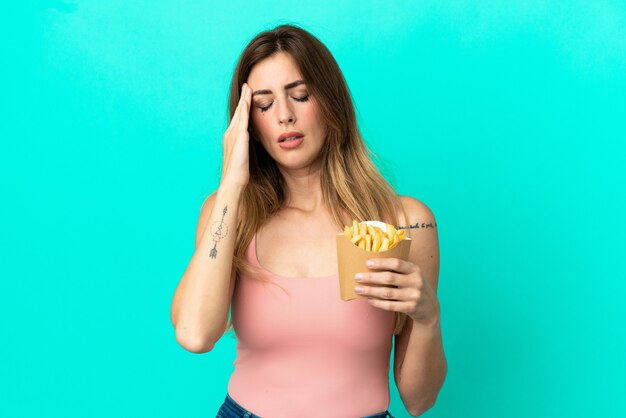 Blanke vrouw met gebakken chips geïsoleerd op blauwe achtergrond met hoofdpijn