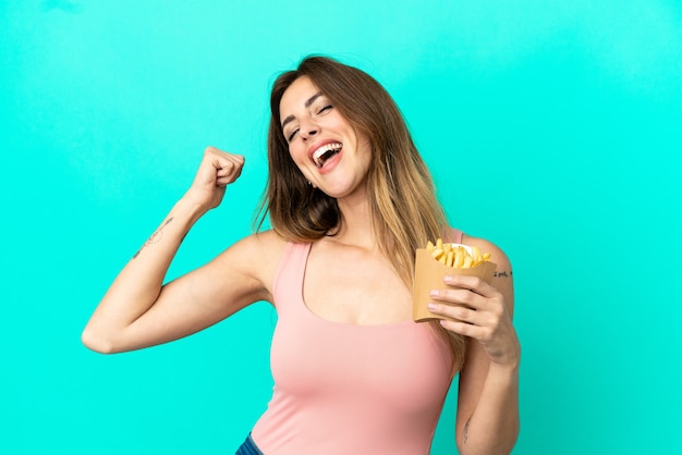 Blanke vrouw met gebakken chips geïsoleerd op een blauwe achtergrond die een overwinning viert