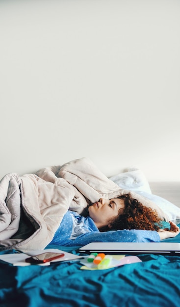 Foto blanke vrouw met krullend haar in blauwe pyjama slaapt na huiswerk ochtendtijd