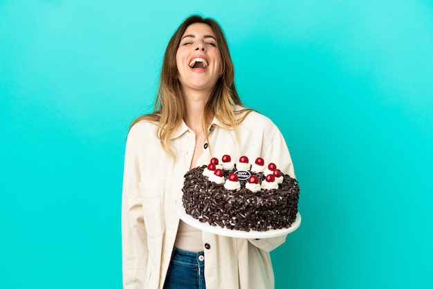 Blanke vrouw met verjaardagstaart geïsoleerd op blauwe achtergrond lachen