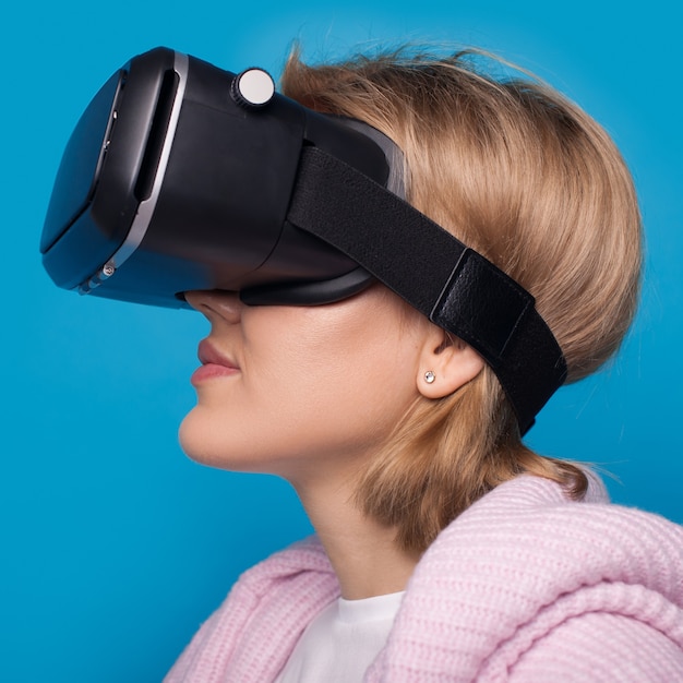 Blanke vrouw met vr-headset poseren op een blauwe muur met vrije ruimte