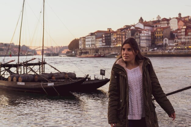 Blanke vrouw poseren voor een typische Porto-boot met wijnvaten bij zonsondergang