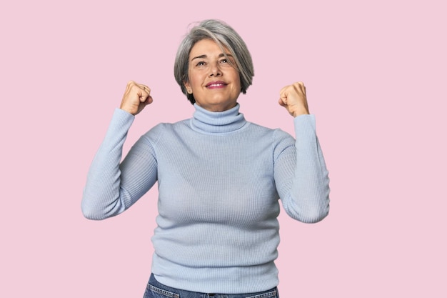 blanke vrouw van middelbare leeftijd op de achtergrond van de studio die een overwinningspassie viert