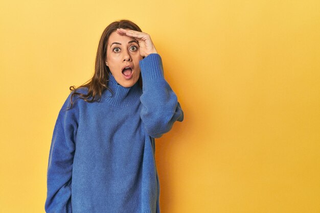 Foto blanke vrouw van middelbare leeftijd op geel schreeuwt luid, houdt de ogen open en de handen gespannen