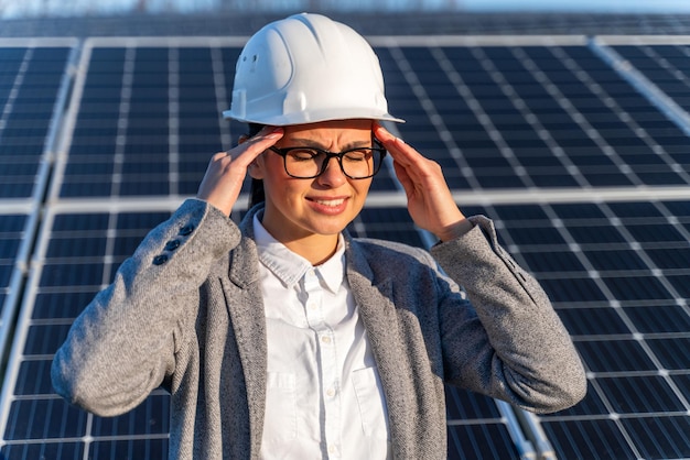 Blanke vrouwelijke ingenieurs met pijn in het hoofd staan bij het zonnepaneel