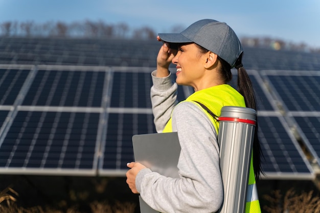 Blanke vrouwelijke monteur in uniform met pet met behulp van digitale tablet op werkruimte Technicus vrouwelijke ingenieur na bespreking van plannen voor bouw Zonneboerderijconcept