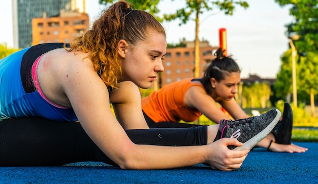 Blanke vrouwen die sportkleding dragen en zich uitstrekken tijdens de buitentraining