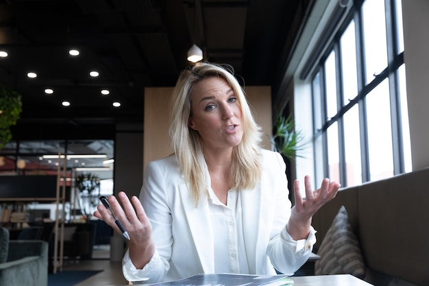 Blanke zakenvrouw die videochat heeft en papierwerk doorneemt in een modern kantoor. zakelijke moderne kantoorwerkplektechnologie.