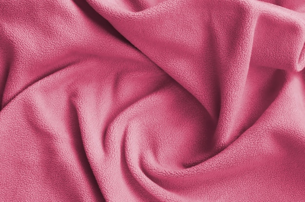 The blanket of furry fleece fabric A background of soft plush fleece material Image toned in Viva Magenta color of the 2023 year