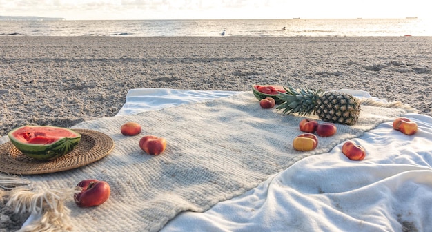 Blanket with fruits on sandy beach picnic concept