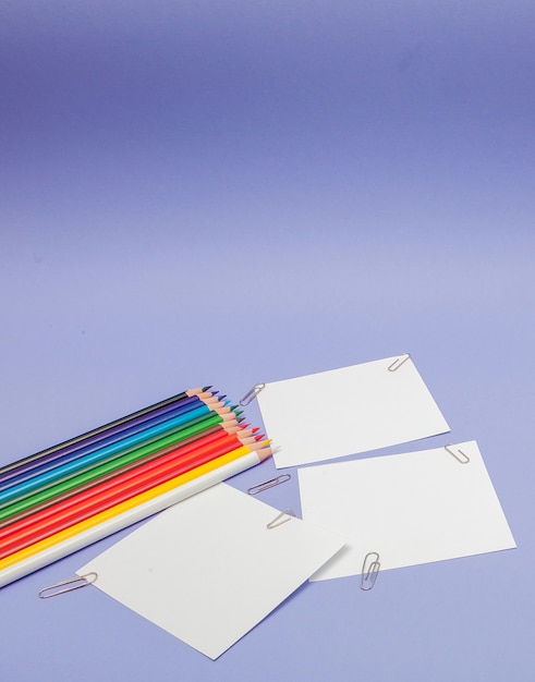 Бланки листов бумаги и цветных карандашей на фиолетовом фоне для проектов и объявлений, копия места