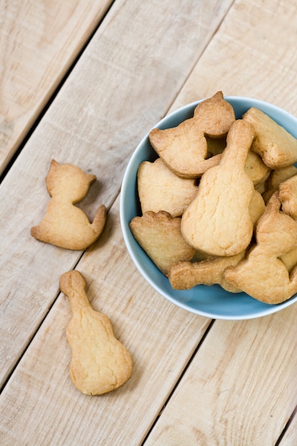 Blauw bord met lekkere koekjes in de vorm van beeldjes van katten en gitaren op de ongeverfde houten tafel