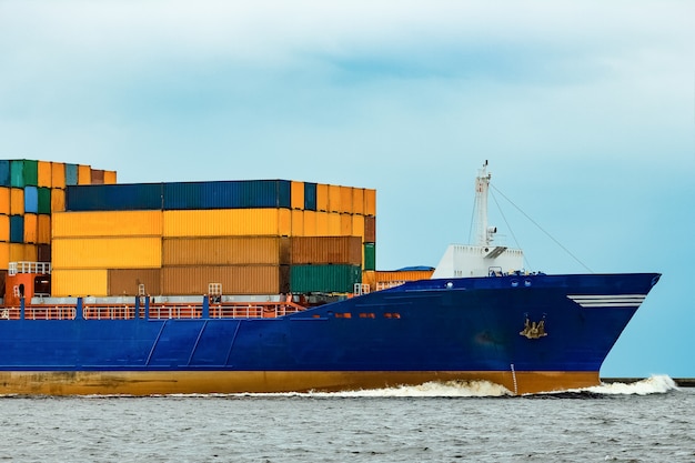 Blauw containerschip volledig geladen vanuit de zee