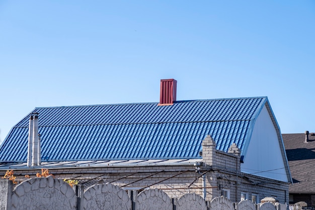 Blauw dak met metalen tegels en rode schoorsteen.