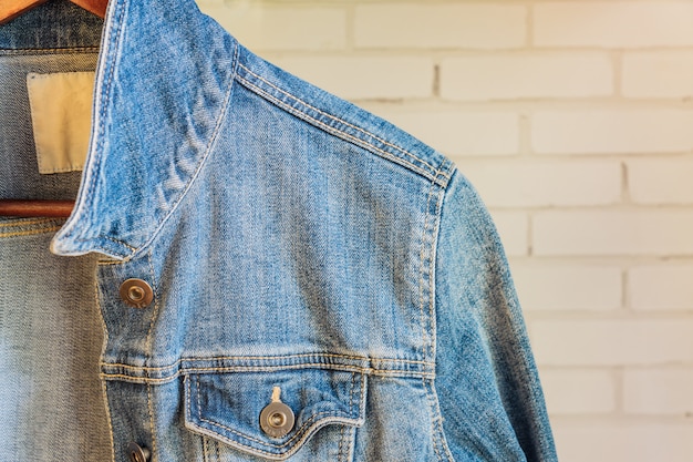 Blauw denim vrouwenjasje op een houten hanger. Trendy kleding.