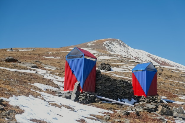 Blauw en rood kleurentoilet. Sanitaire toiletcabine in de met sneeuw bedekte berg.