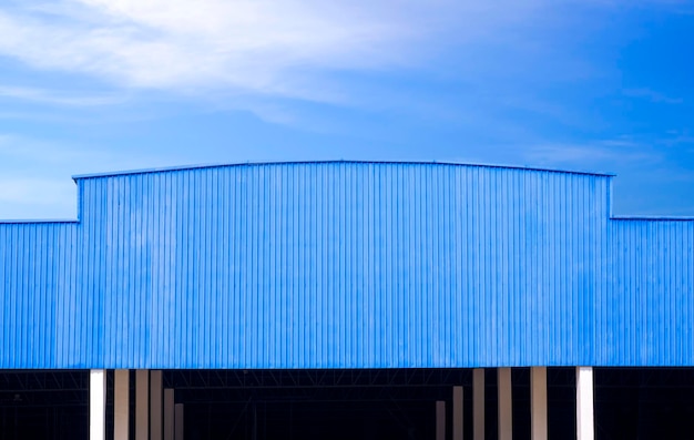 Blauw gegolfd metalen dak van groot industrieel pakhuisgebouw tegen blauwe hemelachtergrond