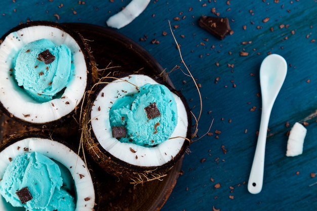 Blauw ijs met chocolade in kokos kom op houten achtergrond. Zomer eten. Bovenaanzicht. Kopieer ruimte.