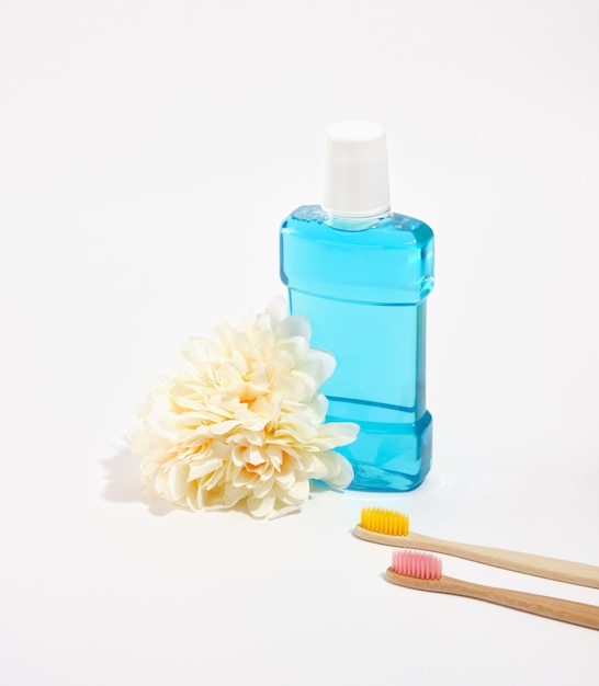 Blauw mondwater en organische bamboes tandenborstels met gekleurde borstels geïsoleerd Verse weelderige bloem