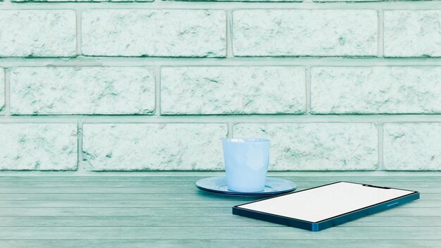 Blauw podium met houten tafel en bakstenen muur met koffiekop en mobiele telefoon technologie en rust