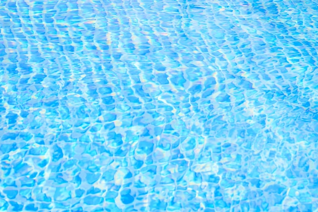 Blauw rimpelwater in het zwembad met reflectie van de zon
