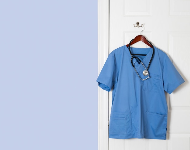 Blauw scrubs-shirt voor medische professional dat aan de deur hangt