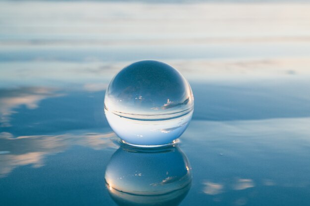 Foto blauw vrijheidsconcept: de kristallen bol weerspiegelt water en lucht in blauw. prachtige creatieve landschapsfotografie