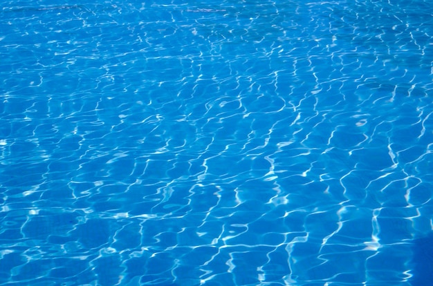 Blauw zwembadwater met reflecties van de zon