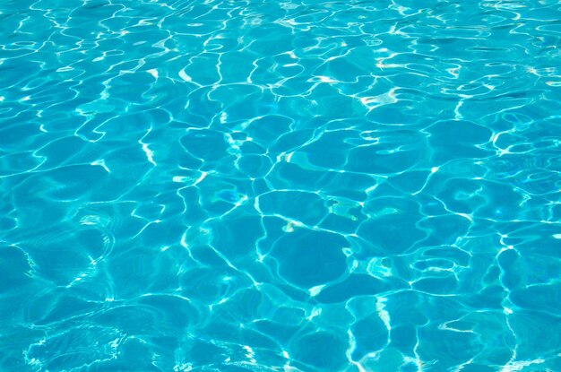 Blauw zwembadwater met reflecties van de zon