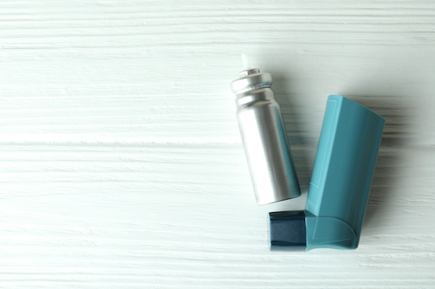 Blauwe astma-inhalator op witte houten tafel