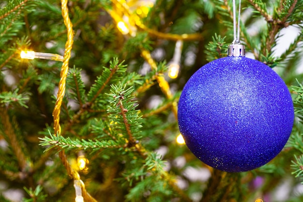 Blauwe bal en lichtkoord op twijgen van kerstboom