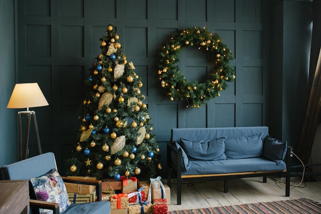 Blauwe bank met kussens en kerstkrans aan de muur in de woonkamer in de loftstijl.