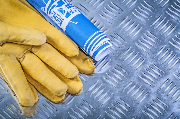 Blauwe blauwdrukken lederen beschermende handschoenen op gegroefde metalen plaat bouwconcept