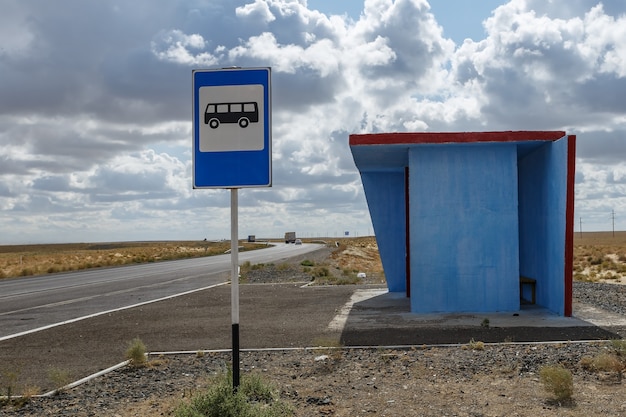 Blauwe bushalte en een bushalteteken op een pijler in de steppe van kazachstan