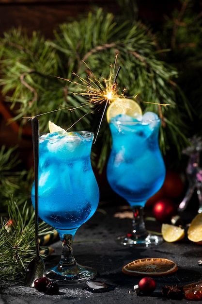 Blauwe cocktail in een groot glas met ijs en schijfjes citroen op een houten ondergrond